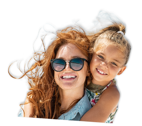 Smiling mother and beautiful daughter having fun on the beach. Portrait of happy woman giving a piggyback ride to cute little girl with copy space. Portrait of happy blonde kid embracing her mom wearing spectacles at beach during summer vacation.